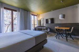 
a room with a bed, chair, table and window at Hotel Plaza Mercado & Spa in Valencia
