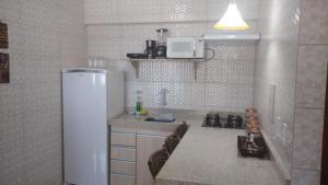 La cuisine blanche est équipée d'un réfrigérateur et d'un évier. dans l'établissement Lindo apartamento frente ao mar., à São José da Coroa Grande