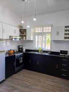 a kitchen with white cabinets and black counter tops at AVA BEACH HOUSE in Blue Bay