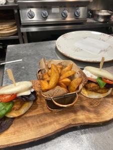three sandwiches and french fries on a wooden cutting board at Соколови къщи in Gabrovo