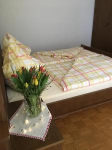 een vaas met bloemen op een tafel naast een bed bij Appartements Caroline in Ossiach