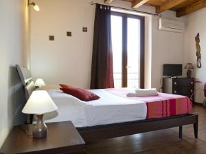 a bedroom with a bed with a lamp and a window at Cuscino e Cappuccino B&B in Alghero