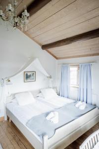 a bedroom with a large white bed with blue curtains at Hotell Klockargården in Tällberg