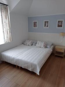 a white bed in a room with a wooden floor at Szanta in Jastarnia