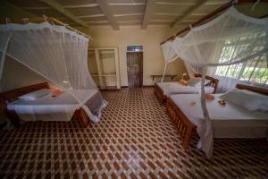 a bedroom with two beds with mosquito nets on them at Meremeta Lodge in Utende