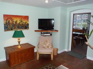 a living room with a tv and a chair and a lamp at Kwerky Cottage in North Lydbury