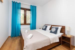 a bedroom with a large bed with blue curtains at Villa 4 Pory Roku by Renters in Jastrzębia Góra