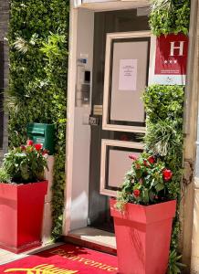 une porte rouge avec deux plantes en pot dans l'établissement Hotel le Romanesque, à Cannes