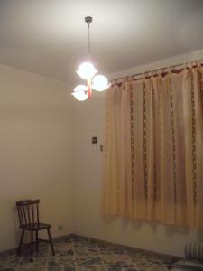 um quarto com um lustre, uma cadeira e uma janela em Calatafimi Segesta - Appartamento Garibaldi em Calatafimi