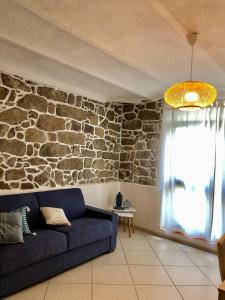 sala de estar con sofá azul y pared de piedra en Il Gabbiano case vacanza, en Santa Teresa Gallura