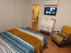 1 dormitorio con 1 cama, 1 silla y TV en Apartamento wifi alta velocidad, Netflix, piscina y jardin privados en Miami Platja