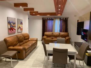 - un salon doté d'un mobilier en cuir brun et d'une table dans l'établissement XL Bugibba Home, à San Pawl il-Baħar