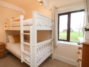 a white bunk bed in a room with a window at Barn Cottage in Bude