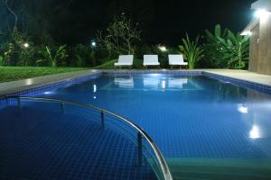 una piscina por la noche con 2 sillas en Happyland Private Villa en Alibaug