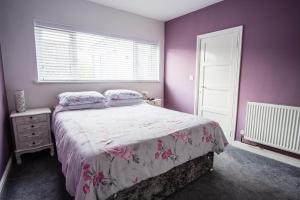 Schlafzimmer mit einem Bett mit rosa Wänden und einem Fenster in der Unterkunft Tallets Apartment with Balcony & Parking in Tewkesbury