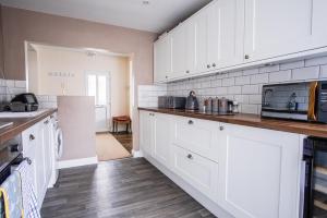 eine Küche mit weißen Schränken und einer Arbeitsplatte in der Unterkunft Tallets Apartment with Balcony & Parking in Tewkesbury