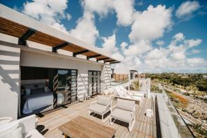 eine Terrasse mit weißen Stühlen und ein Bett auf einem Balkon in der Unterkunft Penthouse H70 St Antoine Residence in Île dʼAmbre
