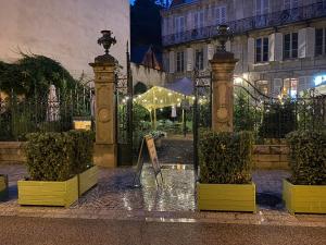 um reflexo de um portão com plantas em frente a um edifício em Hôtel de Colbert em Aubusson