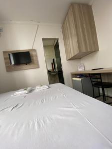 a large white bed in a room with a kitchen at Hotel Premier in Brasília