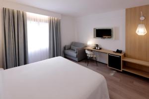 a hotel room with a bed and a chair and a desk at Sercotel Carlos III in Cartagena