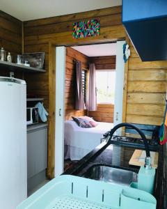 a kitchen with a sink and a room with a bed at Bangalôs Floripa - Tiny House in Florianópolis