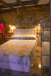 una camera da letto con un letto bianco in un muro di pietra di Casa en zona medieval a Monforte de Lemos
