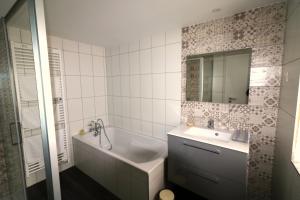 y baño con bañera, lavabo y espejo. en Gîte Sainte Odile en Obernai