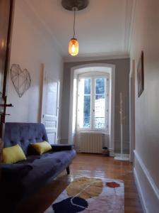 a living room with a blue couch and a window at Tulle Centre : grand et bel appartement in Tulle