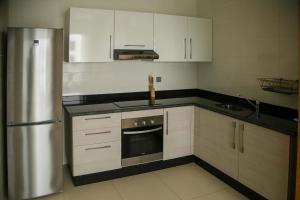 a kitchen with white cabinets and a stainless steel refrigerator at Zephyr Agadir in Agadir