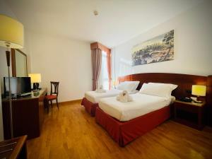 a hotel room with two beds and a television at Hotel Hermitage in Poggio a Caiano