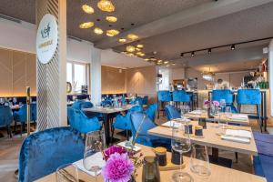 uma sala de jantar com cadeiras e mesas azuis e mesa de trabalho em I LOVE SYLT Hotel Terminus ADULTS ONLY em Westerland