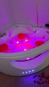 uma banheira branca com luzes cor-de-rosa num quarto em Nid d'amour baignoire/jacuzzi em Nice