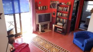 uma sala de estar com uma televisão e uma cadeira azul em CASA FLORES em Los Llanos de Aridane