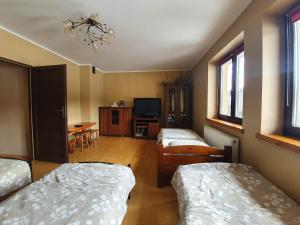 a room with two beds and a tv and a table at Domki u Gretka in Lutowiska