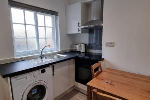 a kitchen with a sink and a washing machine at 2 BED 2 BATH & FREE PARKING - 10 MINS TO MADEJSKI STADIUM in Theale
