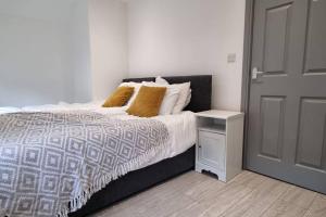 um quarto com uma cama com uma mesa de cabeceira e uma porta em 2 BED 2 BATH & FREE PARKING - 10 MINS TO MADEJSKI STADIUM em Theale