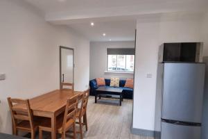 a kitchen and dining room with a table and a refrigerator at 2 BED 2 BATH & FREE PARKING - 10 MINS TO MADEJSKI STADIUM in Theale