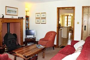 een woonkamer met een bank en een open haard bij Rowan Cottage in Hawkshead