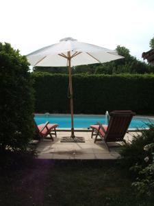 two chairs and an umbrella next to a pool at Château Beauséjour in Listrac-Médoc