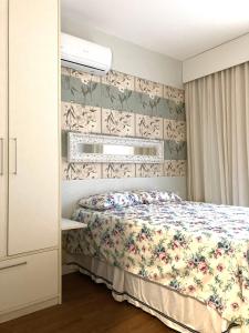 a bedroom with a bed with a floral bedspread at Palm beach, Porto das dunas próximo ao Beach Park in Aquiraz