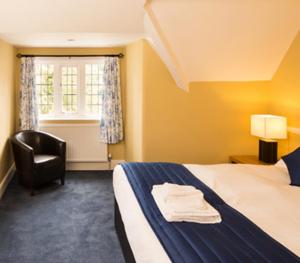 a bedroom with a bed and a chair and a window at The Inn at Woodhall Spa in Woodhall Spa