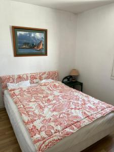 a bedroom with a bed with a red and white blanket at appartement spacieux et lumineux proche de la plage in Quimiac