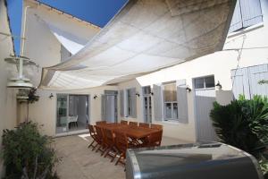 un patio con una mesa de madera y sillas bajo toldo en Région PACA -Provence Alpes Côte d'Azur - Camargue, en Port-Saint-Louis-du-Rhône