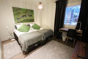 um quarto com uma cama com almofadas verdes e uma janela em Hotel Hullu Poro em Levi