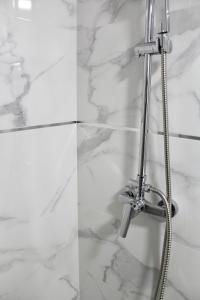 a shower head in a bathroom with white marble walls at WISH SUITE BASILICA in Seville
