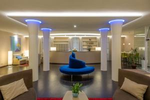 a lobby with a blue chair with a hat on it at Hotel San Marco in Lucca