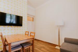 a dining room with a table and a tv on a wall at Apartamenty Przy Plaży in Sopot