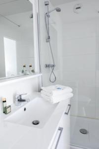 y baño blanco con lavabo y ducha. en Hotel Thermes Les Ecureuils en Dax