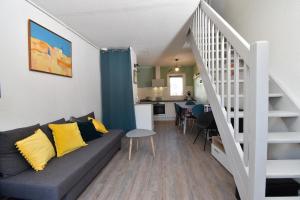 ein Wohnzimmer mit einem Sofa und einer Treppe in der Unterkunft Maison T3 proche plage in Le Grau-du-Roi