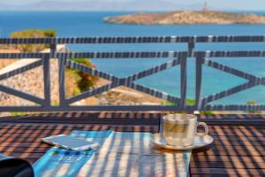a cup of coffee on a table with a cell phone at Sunrise Beach Suites in Azolimnos Syros